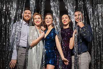 Image showing happy friends in party clothes with tinsel curtain
