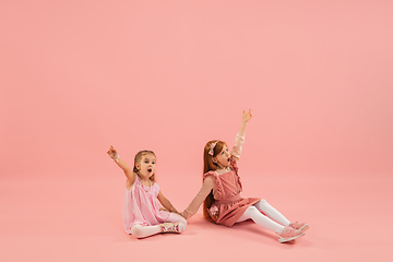 Image showing Childhood and dream about big and famous future. Pretty little girls isolated on coral pink background