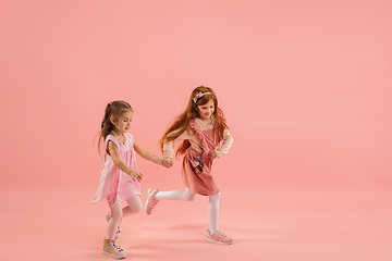 Image showing Childhood and dream about big and famous future. Pretty little girls isolated on coral pink background