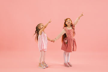 Image showing Childhood and dream about big and famous future. Pretty little girls isolated on coral pink background