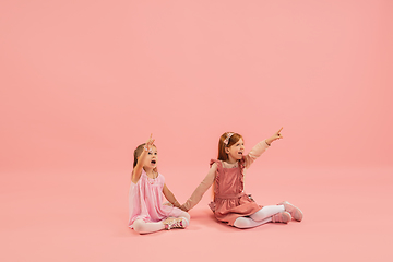 Image showing Childhood and dream about big and famous future. Pretty little girls isolated on coral pink background