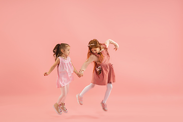 Image showing Childhood and dream about big and famous future. Pretty little girls isolated on coral pink background