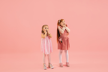 Image showing Childhood and dream about big and famous future. Pretty little girls isolated on coral pink background