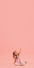 Image showing Childhood and dream about big and famous future. Pretty longhair girl isolated on coral pink background