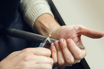 Image showing Close up hands of jeweller, goldsmiths making of golden ring with gemstone using professional tools.