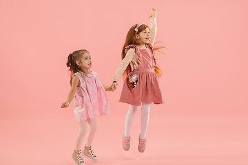 Image showing Childhood and dream about big and famous future. Pretty little girls isolated on coral pink background