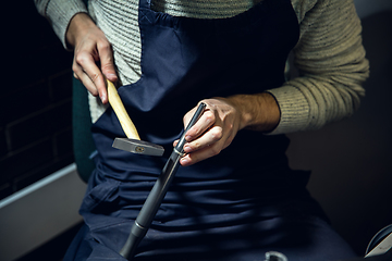 Image showing Close up hands of jeweller, goldsmiths making of silver ring with gemstone using professional tools.