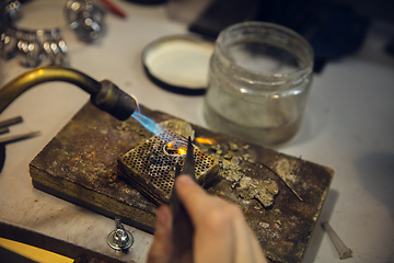 Image showing Close up hands of jeweller, goldsmiths making of silver ring with gemstone using professional tools.