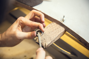 Image showing Close up hands of jeweller, goldsmiths making of silver ring with gemstone using professional tools.