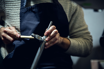 Image showing Close up hands of jeweller, goldsmiths making of silver ring with gemstone using professional tools.