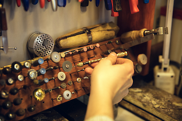 Image showing Close up hands of jeweller, goldsmiths making of silver ring with gemstone using professional tools.