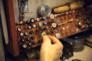 Image showing Close up hands of jeweller, goldsmiths making of silver ring with gemstone using professional tools.