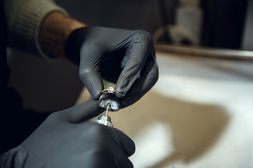 Image showing Close up hands of jeweller, goldsmiths making of silver ring with gemstone using professional tools.