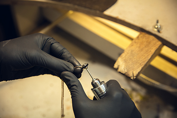 Image showing Close up hands of jeweller, goldsmiths making of silver ring with gemstone using professional tools.