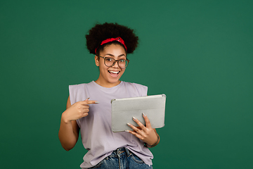 Image showing African-american woman\'s portrait isolated on green studio background with copyspace