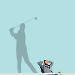 Image showing Young man dreaming about future in big sport during his work in office. Becoming a legend. Shadow of dreams on the wall behind him. Copyspace.