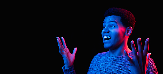 Image showing African-american man\'s portrait isolated on black studio background in multicolored neon light