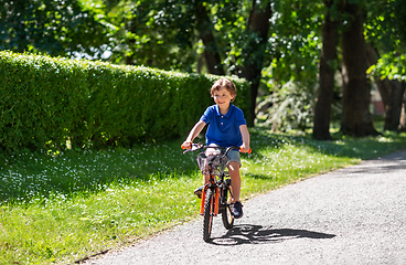 Image showing happy little boy riding bicycle at summer park