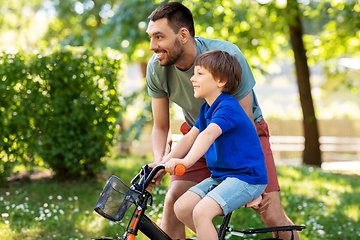 Image showing father teaching little son to ride bicycle at park