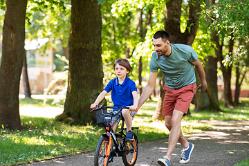 Image showing father teaching little son to ride bicycle at park