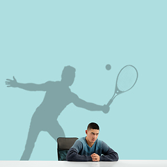 Image showing Young man dreaming about future in big sport during his work in office. Becoming a legend. Shadow of dreams on the wall behind him. Copyspace.