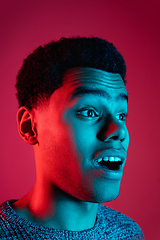 Image showing African-american man\'s portrait isolated on red studio background in multicolored neon light