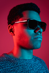 Image showing African-american man\'s portrait isolated on red studio background in multicolored neon light