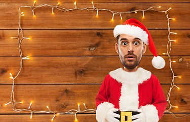 Image showing surprised santa over garland on wooden background