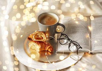 Image showing croissants, cup of coffee, book and glasses in bed