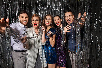 Image showing happy friends in party clothes with tinsel curtain