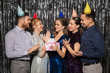 Image showing happy friends in party hats with birthday gift