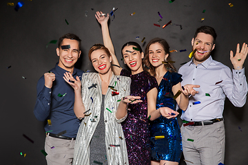 Image showing happy friends at party under confetti over black