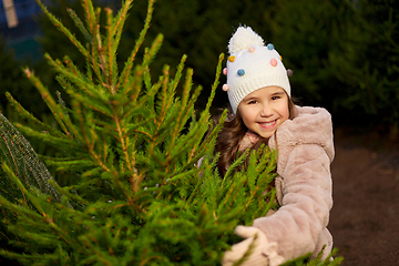 Image showing little girl choosing christmas tree at market