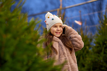 Image showing girl calling on smartphone over christmas trees