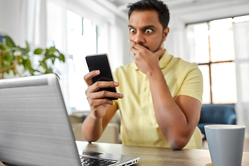 Image showing shocked indian man with smartphone working at home