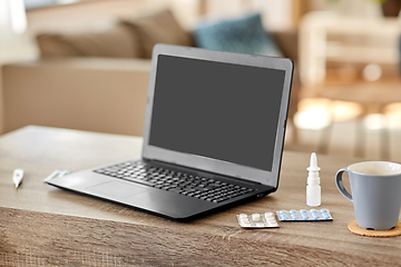 Image showing laptop computer, drugs and cup on table at home