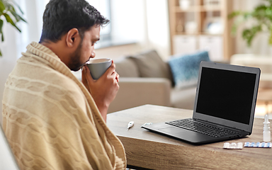 Image showing sick indian man with laptop drinking tea at home