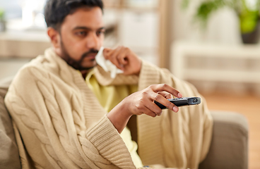 Image showing sick man with paper tissue and tv remote at home