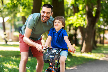 Image showing father teaching little son to ride bicycle at park