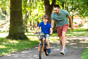 Image showing father teaching little son to ride bicycle at park