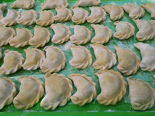 Image showing Semi-finished dumplings on a green kitchen tray with flour