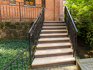 Image showing A beautiful staircase with metal railings rises to a red brick building