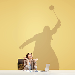 Image showing Young woman dreaming about fantasy worlds during her work in office. Becoming a legend. Shadow of dreams on the wall behind her. Copyspace.