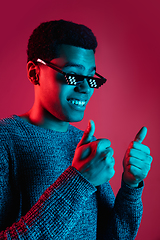 Image showing African-american man\'s portrait isolated on red studio background in multicolored neon light