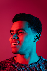 Image showing African-american man\'s portrait isolated on red studio background in multicolored neon light