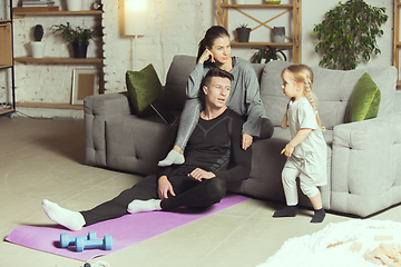 Image showing Young family resting after exercising fitness, aerobic, yoga at home, sporty lifestyle. Getting active during lockdown, quarantine. Home gym.