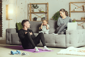 Image showing Young family resting after exercising fitness, aerobic, yoga at home, sporty lifestyle. Getting active during lockdown, quarantine. Home gym.