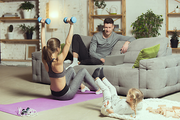 Image showing Young woman exercising fitness, aerobic, yoga at home, sporty lifestyle. Getting active during lockdown, quarantine. Home gym.