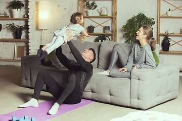 Image showing Young family resting after exercising fitness, aerobic, yoga at home, sporty lifestyle. Getting active during lockdown, quarantine. Home gym.