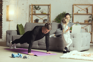 Image showing Young man exercising fitness, aerobic, yoga at home, sporty lifestyle. Getting active during lockdown, quarantine. Home gym.